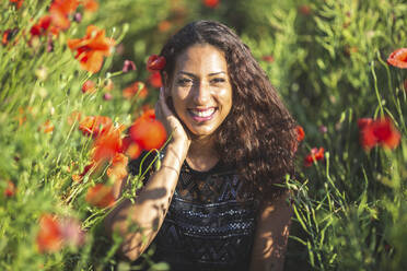 Portrait of smiling young woman in poppy field - ASCF01430