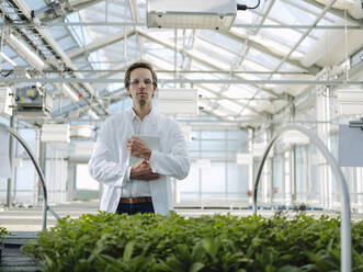 Portrait of a confident scientist holding tablet in a greenhouse - JOSEF01587