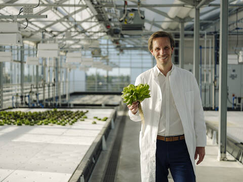 Portrait of a smiling scientist holding lettuce in a greenhouse stock photo