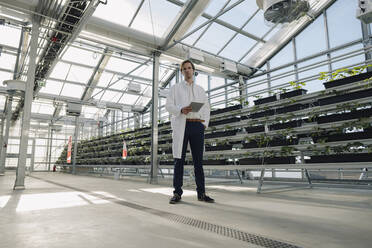 Scientist holding tablet in a greenhouse - JOSEF01613