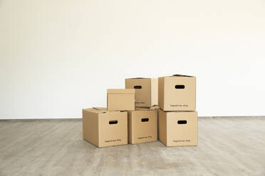 Cardboard boxes on floor against white wall in new house - MJFKF00541