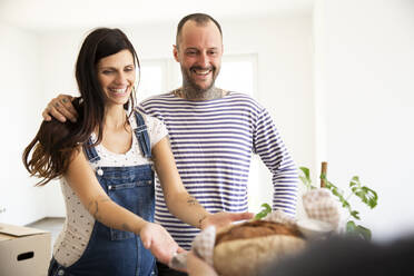 Woman giving bread and salt to new neighbors at home - MJFKF00568