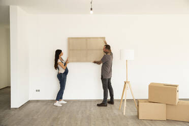 Couple carrying window frame while moving in new house - MJFKF00624