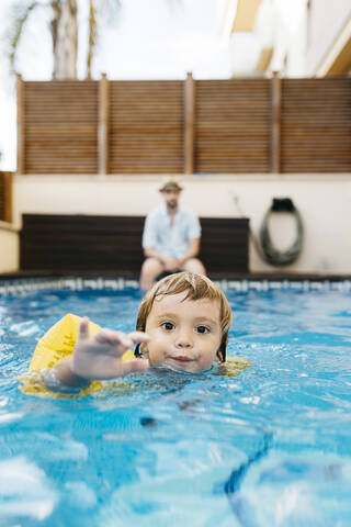 Kleines Mädchen im Schwimmbad, ihr Onkel am Beckenrand, lizenzfreies Stockfoto