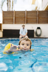 Kleines Mädchen im Schwimmbad, ihr Onkel am Beckenrand - JRFF04697