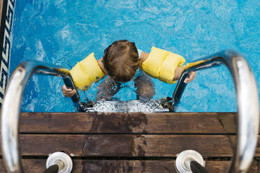 Little girl on ladder of pool - JRFF04698