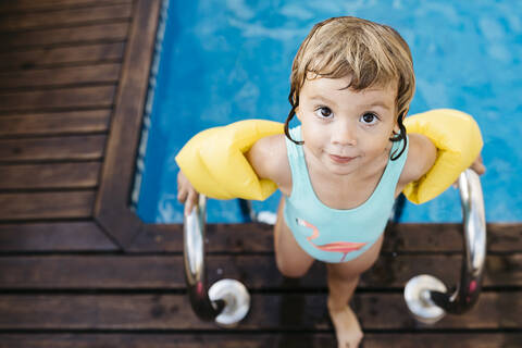 Little girl with armbands at ladder of swimming pool stock photo