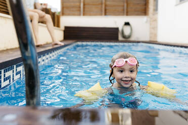 Little girl with swimming goggles in swimming pool - JRFF04706
