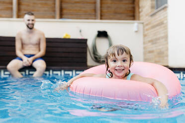 Kleines Mädchen mit Schwimmreifen und ihrem Onkel im Schwimmbad - JRFF04716