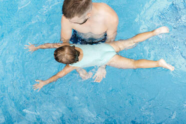 Kleines Mädchen, das mit seinem Onkel im Schwimmbad schwimmen lernt - JRFF04718