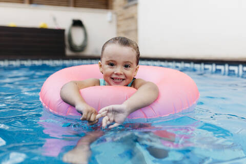 Portrait of little girl with floating tire in pool stock photo