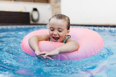 Porträt eines kleinen Mädchens mit schwimmendem Reifen im Pool - JRFF04725