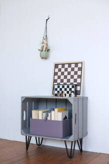 Chess boards lying on top of DIY bookshelf made of wooden crate - GISF00636