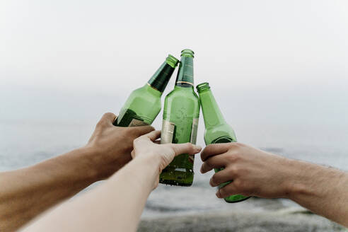 Hände von drei Freunden, die mit Bierflaschen anstoßen - AFVF07063