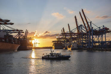 Deutschland, Hamburg, Motorboot fahren im Hamburger Hafen bei Sonnenuntergang - ASCF01446