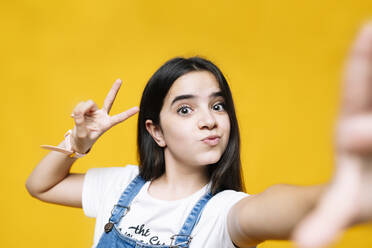 Mädchen mit Friedenszeichen vor gelbem Hintergrund - DGOF01252
