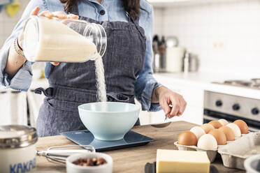 Frau wiegt Mehl auf einer Küchenwaage für die Zubereitung von Kuchen zu Hause - MSUF00292