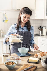 Schöne Frau wiegt Mehl auf Küchenwaage für Backen Kuchen zu Hause - MSUF00293