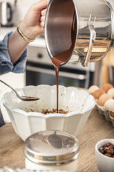 Woman hand pouring melted chocolate in bowl at kitchen - MSUF00310