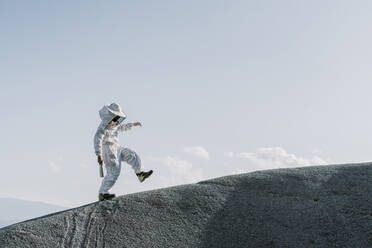 Man wearing a beekeeper dress stepping on a hill - AFVF07075