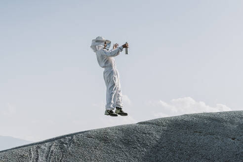 Mann im Imkerkleid springt auf einen Hügel - AFVF07079