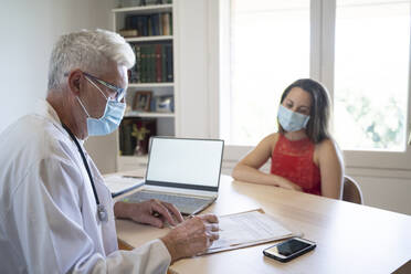 Ein Arzt prüft die Krankenakte eines Patienten, während er in der Klinik sitzt - AFVF07112