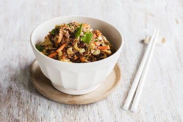 Chopsticks and bowl of fried red rice with vegetables - EVGF03747
