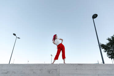 Young dancer with hand on hip posing against clear sky - TCEF01027