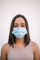 Portrait of beautiful young woman wearing protective face mask - GRCF00337