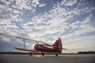 Vintage red Waco airplane sits on runway at sunrise in Maine - CAVF88608