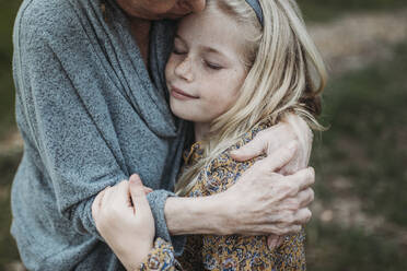 Detailaufnahme eines jungen Mädchens, das von einer älteren Großmutter umarmt wird - CAVF88625