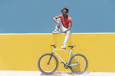 Afroamerikanischer Mann ruht sich in der Nähe des Fahrrads aus - CAVF88626