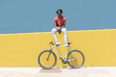 Afroamerikanischer Mann ruht sich in der Nähe des Fahrrads aus - CAVF88629