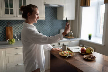 Happy businesswoman making video call during breakfast - CAVF88639