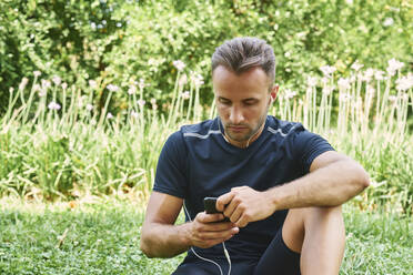 Ein Mann ruht sich nach dem Training auf dem Rasen in einem Park aus. Gesundes und gesundes Leben. Gesundheits- und Sportkonzept. - CAVF88657