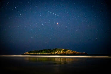 Meteor shooting through the night sky above island in ocean and Mars. - CAVF88671