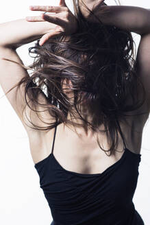 Junge Frau tanzt mit fliegenden Haaren in einem schwarzen Kleid - CAVF88673