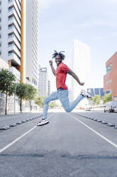 Aufgeregter ethnischer Mann springt auf der Straße - CAVF88685