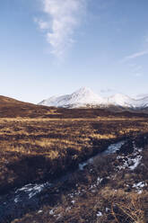 UK, Schottland, Flusslauf auf der Isle of Skye im Winter mit schneebedeckten Bergen im Hintergrund - RSGF00270