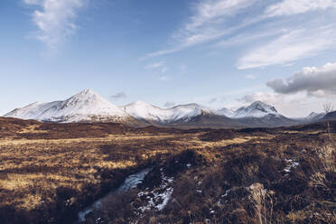 UK, Schottland, Flusslauf auf der Isle of Skye im Winter mit schneebedeckten Bergen im Hintergrund - RSGF00272