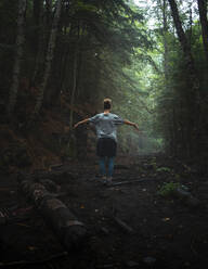 Rückenansicht einer nicht erkennbaren weiblichen Touristin, die mit ausgestreckten Armen auf einem Waldweg steht und die Natur während eines Urlaubs im Algonquin Provincial Park genießt - ADSF13800