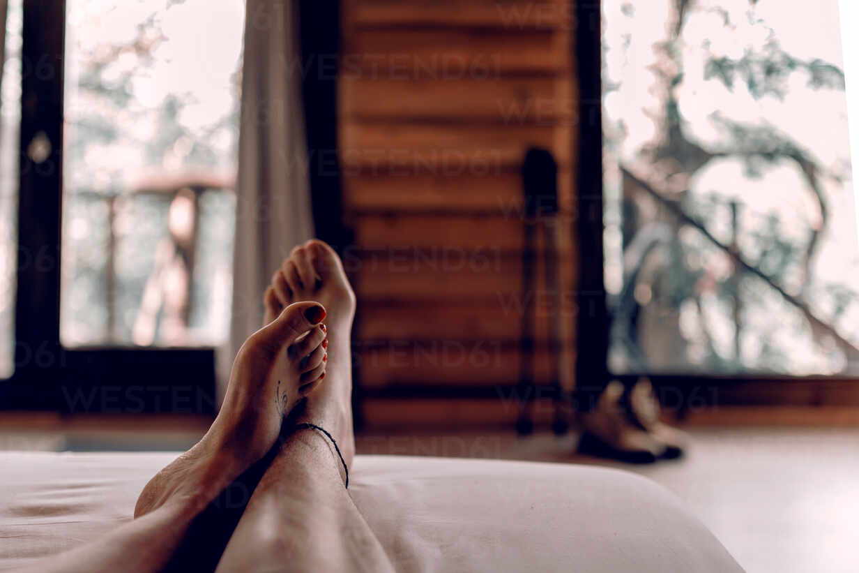 Woman in underwear lying in bed against male feet Stock Photo by