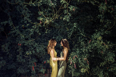 Seitenansicht der charmanten jungen Tochter und schlanken mittleren Alters Mutter schauen sich an und umarmen zärtlich in grünen Garten im Sommer - ADSF14082