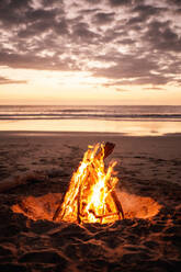 Friedliche Szenerie von gemütlichen Lagerfeuer auf Sandstrand auf dem Hintergrund der ruhigen See unter Sonnenuntergang Himmel - ADSF14108