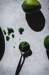 From above basil sugar served on small bowls near lime on rustic table with shadows lights - ADSF14110