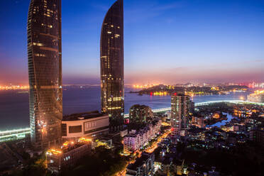 Von oben herrlicher Blick auf beleuchtete Straßen des modernen Stadtteils der Küstenstadt Xiamen in China mit modernen Wolkenkratzern gegen den bunten Himmel am Abend - ADSF14157