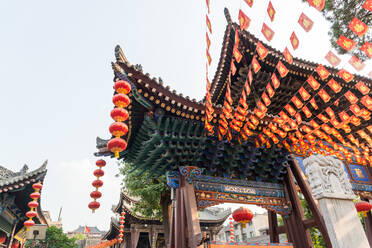 From below of decorative red paper lanterns hanging from curved roofs of Buddhist temples - ADSF14160