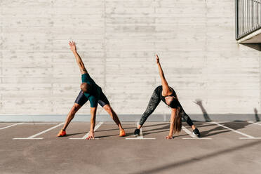 Calm sportsman and sportswoman stretching body bending forward with closed eyes before training - ADSF14185