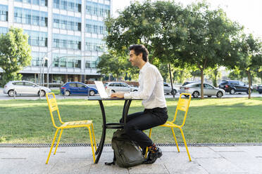 Male entrepreneur using laptop on table while sitting at sidewalk cafe - AFVF07140