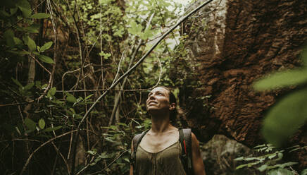Frau beim Trekking im Wald zwischen Felsen und Bäumen - DMGF00122